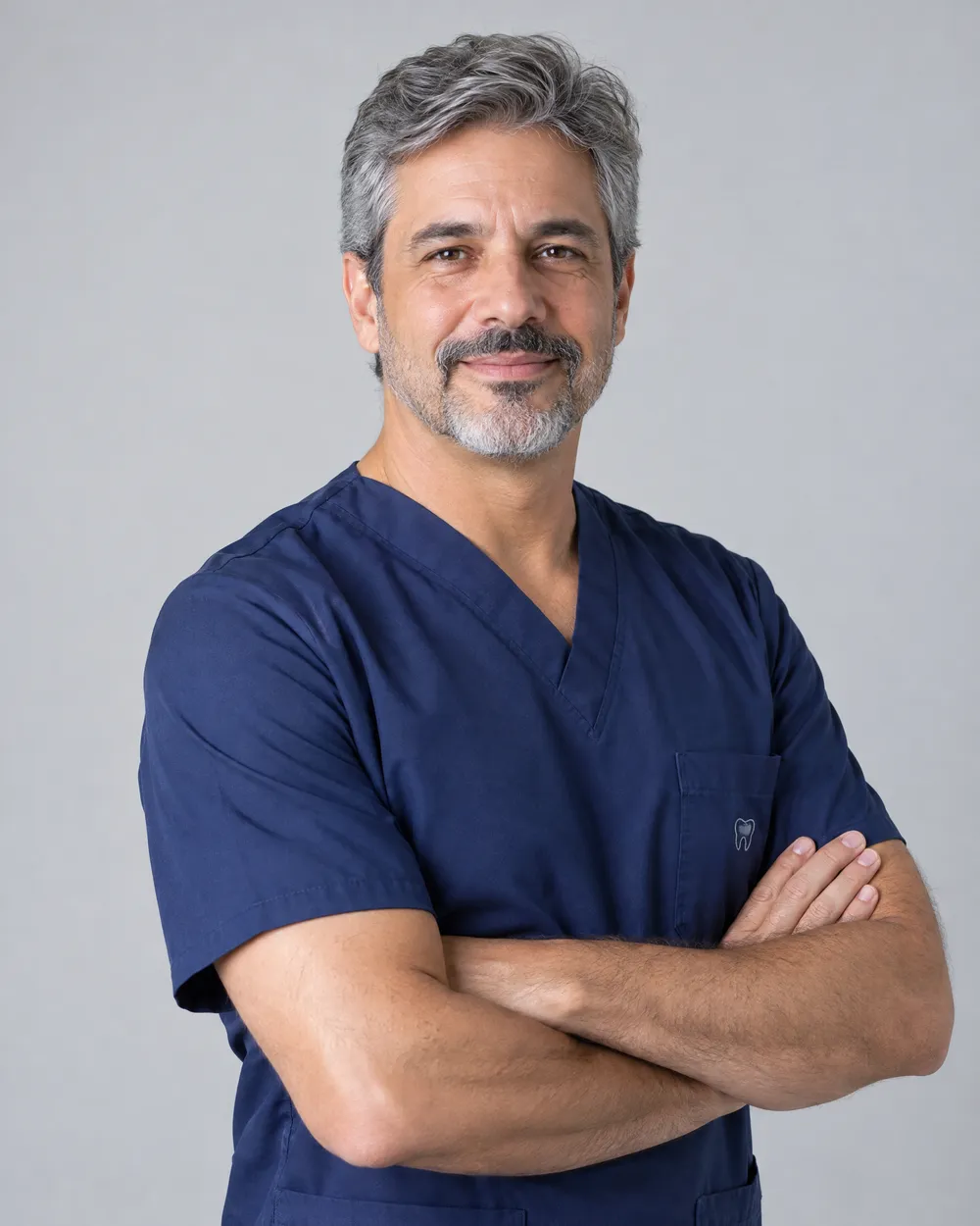Retrato do Dr. Marcelo Antunes, dentista de cabelos grisalhos com uniforme azul-marinho